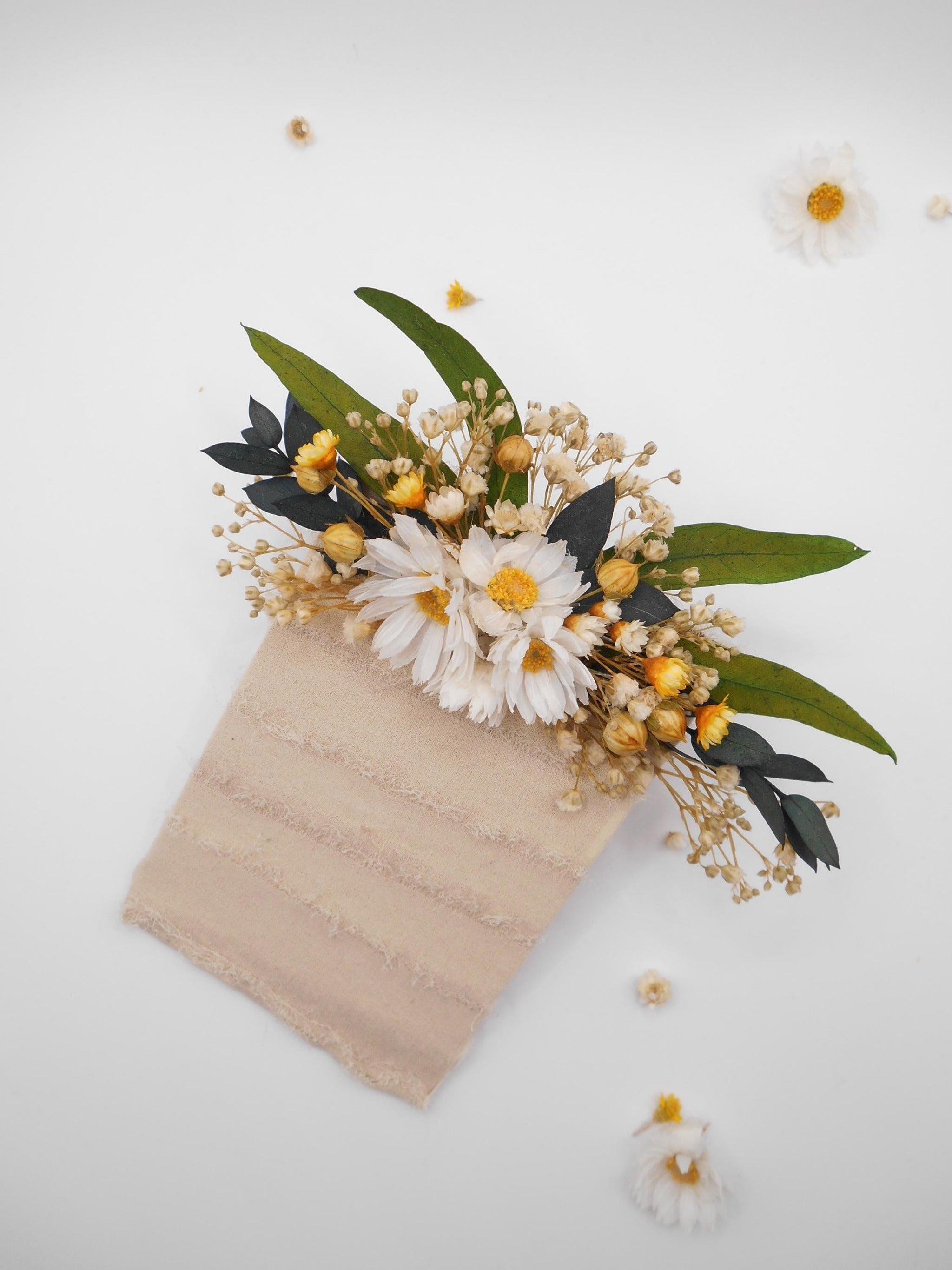 Pocket flower boutonniere with white daisies and yellow flowers, green leaves, and eucalyptus on a white background