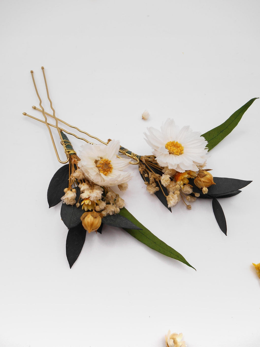 Floral hairpins with white daisies and yellow  flowers, green leaves, and gold accents on a white background