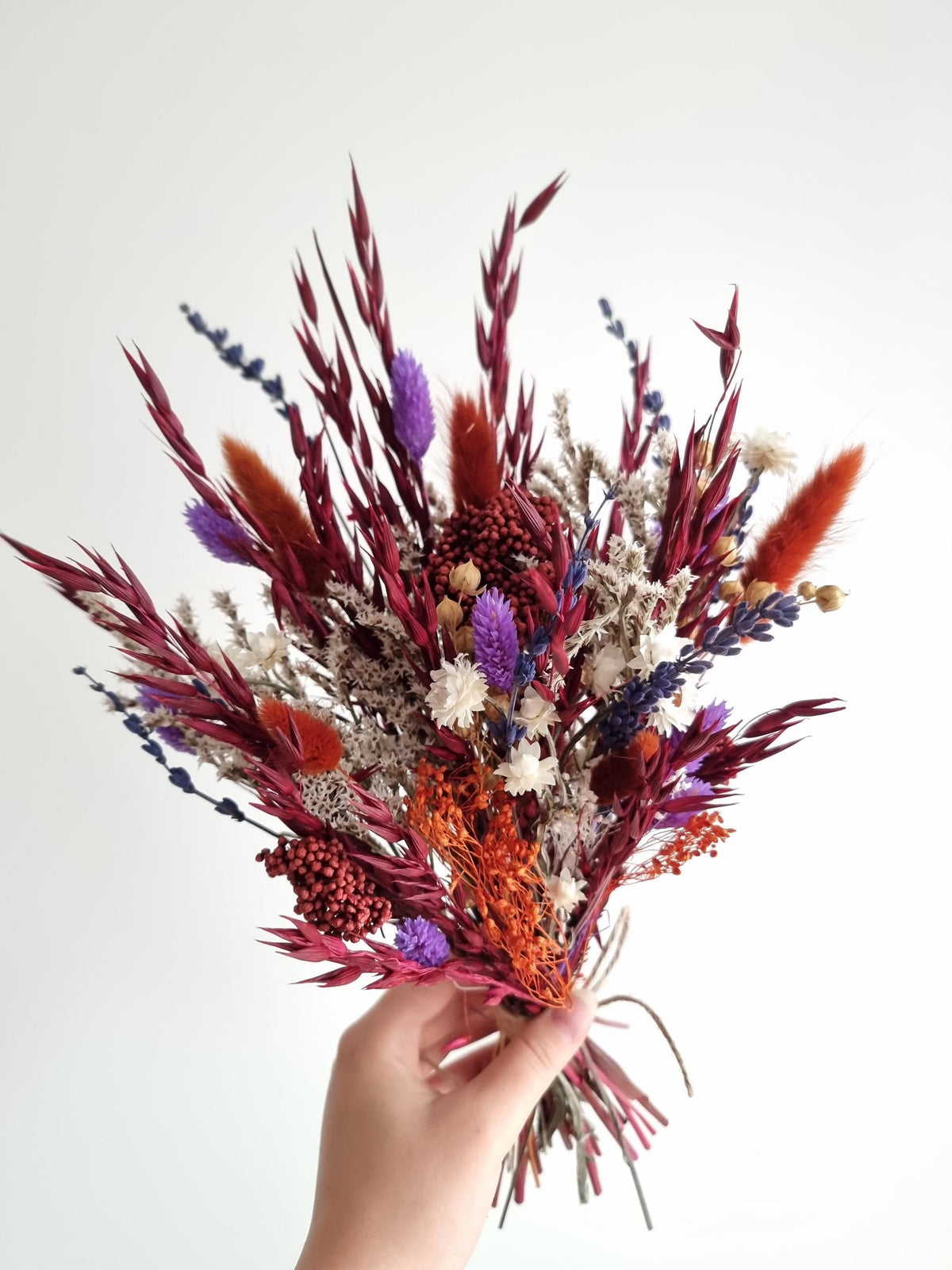 Dramatischer Wildblumenstrauß, tiefrote, terrakottafarbene und violette Trockenblumen, natürliche Wiesenblumen 