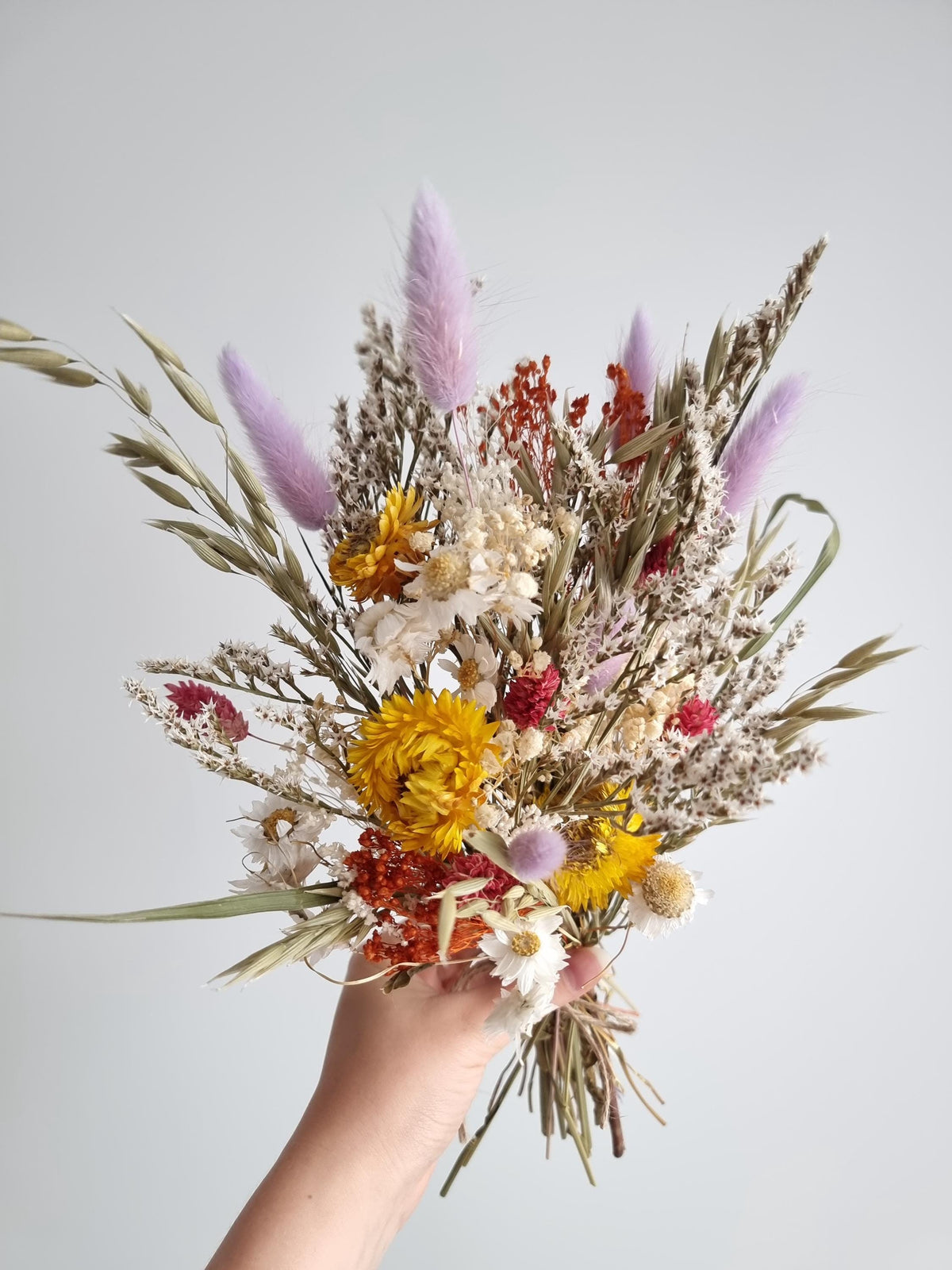 Wildblumenstrauß, pastellfarbene, fliedergelbe und rote Trockenblumen, natürliche Wiesenblumen 